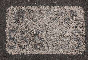 Old asphalt surface with white paint on it close up. Abstract background
