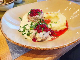 poultry cutlets with mashed potatoes and lingonberry-berry sauce, sprinkled with herbs
