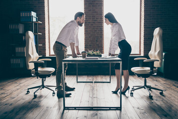 Business competition concept. Profile photo two colleagues classy suits having disagreement conflict standing in modern work station place face to face lean hands on table office indoors - obrazy, fototapety, plakaty