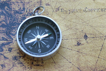 Fototapeta na wymiar Classic round compass on background of old vintage map of world as symbol of tourism with map and compass, travel with map and compass and outdoor activities with map and compass