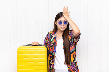 asian young woman raising palm to forehead thinking oops, after making a stupid mistake or...