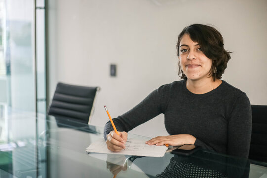 Portrait Of Young Woman Using Pencil At Cafe, She Is Working On Ldesk Computer At A Office