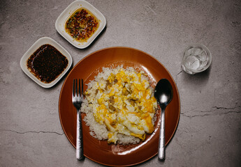 Top view of omelette minced pork on cooked rice with fish sauce over dark concrete copy space...