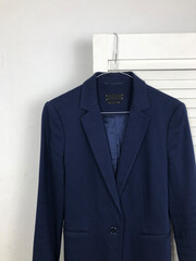 Blank tag on a women's blue jacket on a hanger on a white background