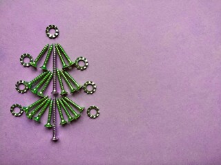 Christmas tree built of construction screws on a lilac background.