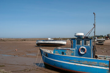 Small boats stranded at low tide on the coast of Norfolk, UK
