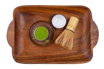 Powdered matcha tea in a cup with bamboo matcha tea whisk also know as chasen on a wooden tray. Top view.