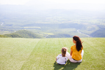 Mutter sitzt mit Kind auf einem Hügel