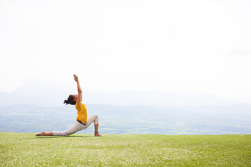 Beautiful woman doing Yoga outside on a hill with a view - 379447349