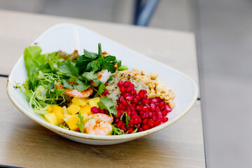 Fresh bowl with vegetables, shrimps, pomegranate seeds and rice. Trendy healthy food and snack.