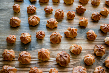 Homemade custard profiteroles laid out on a wooden background.
