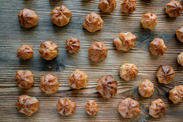 Homemade custard profiteroles laid out on a wooden background.