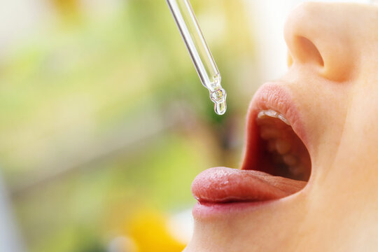 Woman Taking Vitamin D Drops In Mouth From Dropper. Copy Space