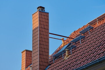chimney on a German rooftop against blue sky, stairs beside