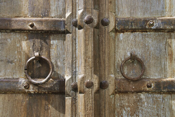 Fototapeta premium Closeup of Old Rustic Wooden Door with Metal Ring Handles