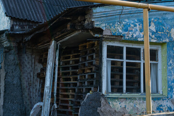 Old dilapidated stone blue house filled with old wooden pallets.