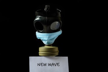A gas mask with a face protective mask on a black background. A plate under the gas mask with the...