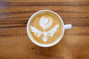 top view of cup of hot latte art on wooden table background