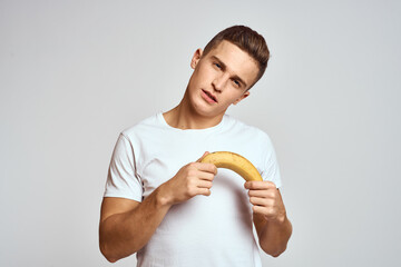 guy with a banana in his hand on a light background fun emotions light background white t-shirt model