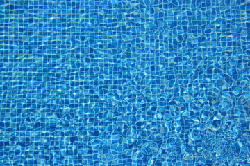 Top view of clear water in a blue tile pool background. Ripple effect