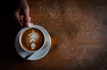 Black coffee in a white coffee cup held by a young woman.