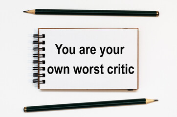 WHITE SPIRAL NOTEBOOK, TWO PENCILS WITH TEXT you are your own worst critic