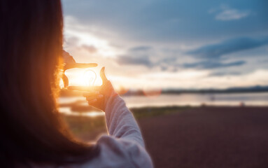 The woman making frame round the sun with her hands in sunrise,Future planning idea concept.