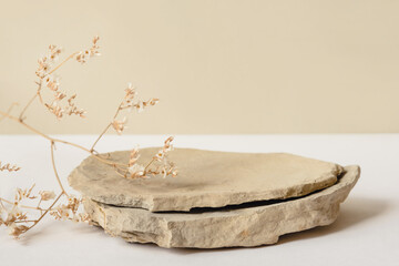 Background for cosmetic products of natural beige color. Stone podium and dry flower on a white...