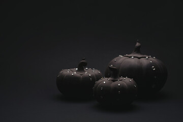 Ceramic pumpkins with rhinestones on a black background. Minimalistic background for autumn...