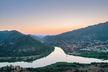 Aerial view of the ancient small illuminated town Mtskheta and view of the merger of two rivers at sunset © Luka