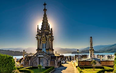 Fotobehang View of historic cemetery in Ortigueira, a coastal village in the Galicia region of Spain  backlight of setting sun. © Lux Blue