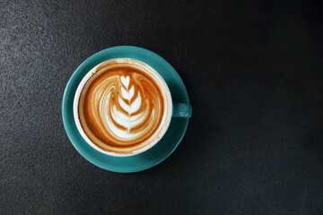 one cup of hot latte with saucer on dark rustic cement background