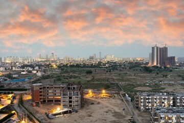 Aerial dusk shot of buuldings with warm orange lights shining out of the newly constructed homes...