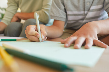 Close up of unrecognizable little boy writing or drawing during development class, focus on hand...