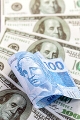 detail of a banknote of one hundred reais from brazil, trapped between banknotes of 100 american...