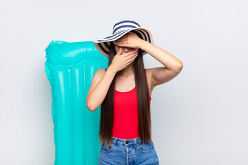 asian young woman covering face with both hands saying no to the camera! refusing pictures or...
