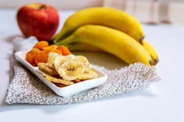 bowl of dried organic banana chips with fresh bananas in the background