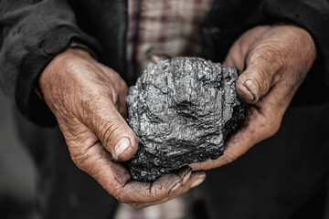 Miner dirty hands holding piece of fossil lignite coal mine