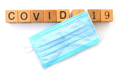 Surgical Mask With Wooden Cubes And Word Covid-19.