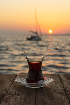 glass of turkish tea on wooden table and sunset background