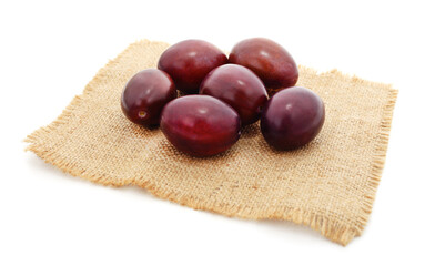 Blue plums with leaves on burlap.