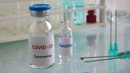 Mini medicine glass bottle and injector with medical materials on the glass table.Vaccine works in the laboratory.Selective focus