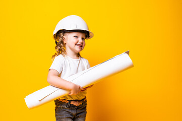 Cute little girl engineer with helmet holding bluepring on yellow background