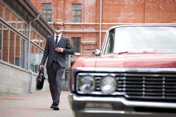 old rich fashionable man next to the luxury automobile, successful male in the suit outdoors. business people concept