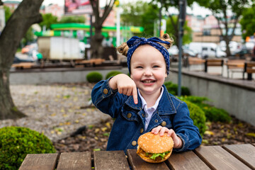 Cute little girl pointed on burger before eat in cafe