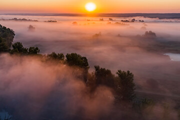 Beautiful panoramic landscape with river valley covered by thick fog in autumn in the early morning. Sunrise.