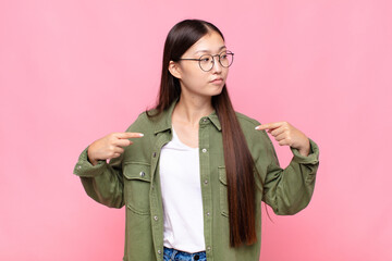 asian young woman looking proud, positive and casual pointing to chest with both hands