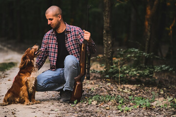 Charismatic guy hunter in a checkered shirt with a weapon. In the autumn forest. Home protection...