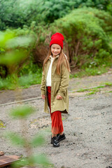 A girl in ordinary autumn clothes on a background of bushes