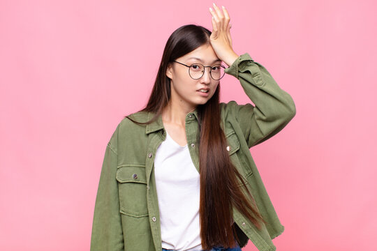 asian young woman raising palm to forehead thinking oops, after making a stupid mistake or remembering, feeling dumb